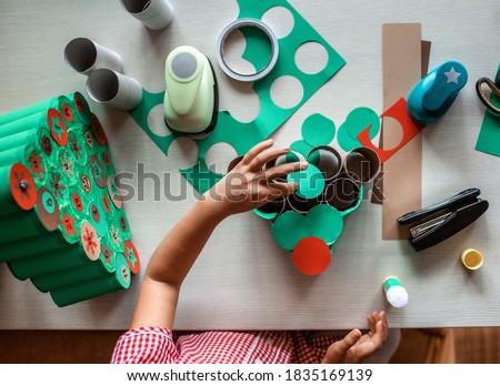Cute little kids making handmade advent calendar with toilet paper rolls at home. Glue, colored paper, cut punch to hide sweets and candies in rolls. Seasonal activity for kids, zero waste holidays