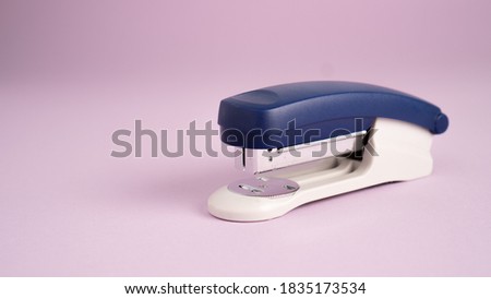 Blue stapler isolated on a purple background. Office supplies. Stapler, staple, paper, cardboard, office equipment Royalty-Free Stock Photo #1835173534