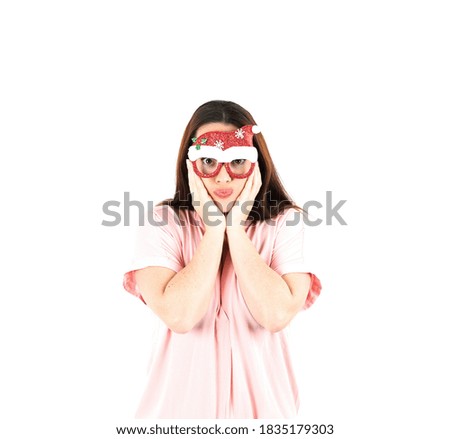Cute young woman with hands on her chin while wearing christmas glasses against a white background