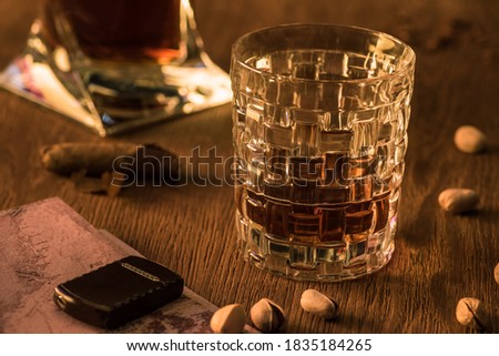 Glass of brandy with lighter on map, pistachios and cigar on wooden table,stock photo
