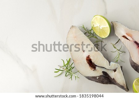 halibut steaks, lime and rosemary on a light marble table, space for text