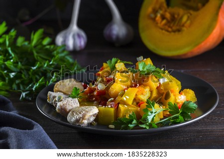 Chicken breast and pumpkin stew with bell peppers, tomatoes, sesame seeds and pumpkin seeds, garnished with parsley.