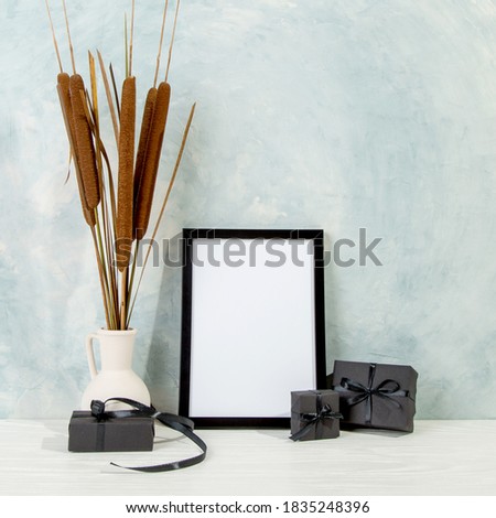 Photo A frame, reeds in a vase and black gifts with black ribbons, concept sale on Black Friday. Copy space.