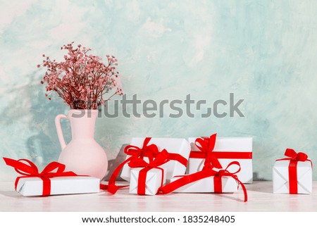 Photo frame with a place for text, next to gifts with red ribbons and vase of dried flowers, the concept of Christmas and holiday. Copy space.