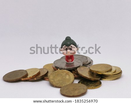 Photo of coins and miniature old woman isolated on white background.Money and finance concept.Life savings.Selective focus.