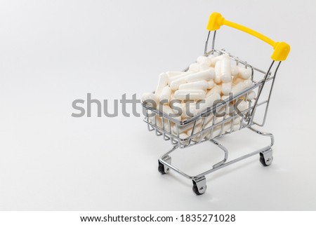 High angle shot of a small shopping cart full of white pills. White background, copy space. Shopping online, buying medicine, pharmaceutical business concepts.