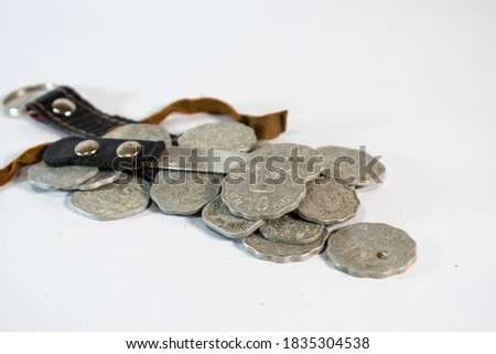Bunch of old Indian currency coins with a small pirate knife and lathered cover on white background 