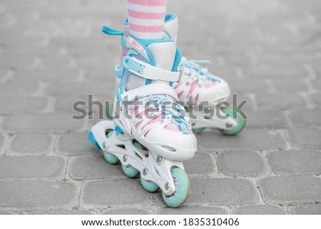 The child is rollerblading in the yard. Girl in pink tights. Childhood and hobby concept.