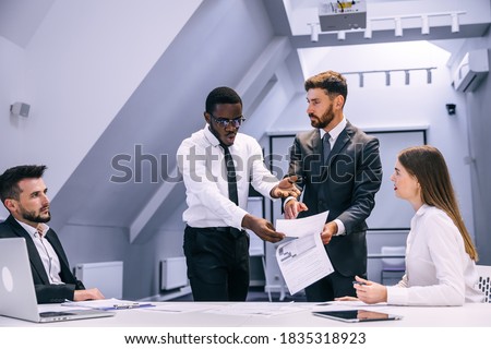 angry african businessman points finger at document boss scolds employee for poor performance, workplace conflict, unpleasant behavior in office Royalty-Free Stock Photo #1835318923