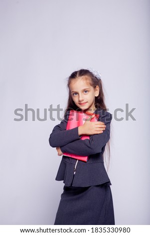 portrait of a girl in strict school clothes on a light gray background