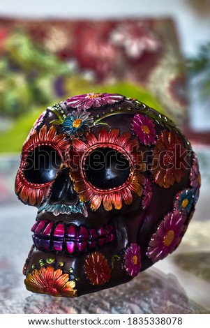 Mexican day of the dead skull with multicolored daisies and purple teeth