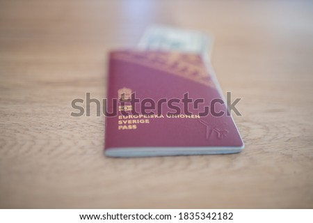 Picture of a Swedish Passport (with the words European Union Sweden Passport in Swedish) with a 20 Thai Baht Bill Partially Inside