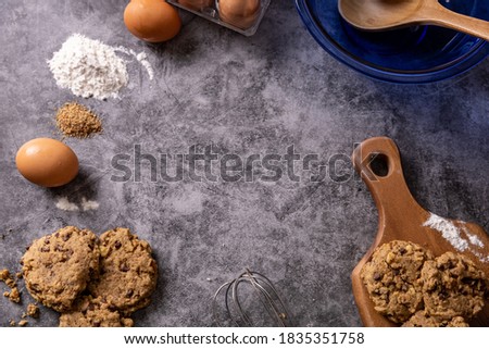 Straight down view of home made cookies with the baking ingredients laid around the concrete countertop, with free space for words or art.