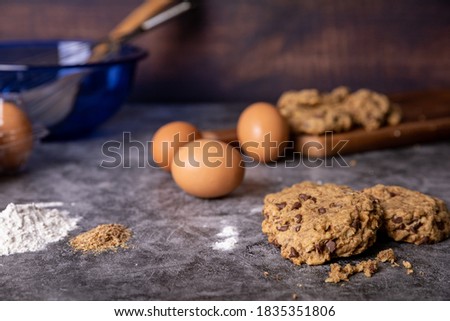 Close up view of home made cookies with the baking ingredients laid around the concrete countertop.