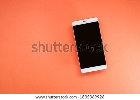 View from above of a smartphone on the orange background 