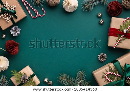 Christmas frame with gift boxes, paper decorations, jingle bells and spruce branches on turquoise background. Holiday background in earth colours.
