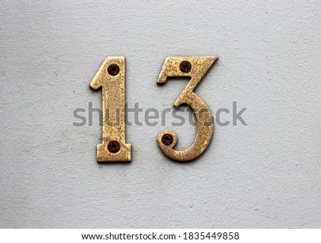 Rusty brass house number plate  with very rusty red screws. Number 13(thirteen)