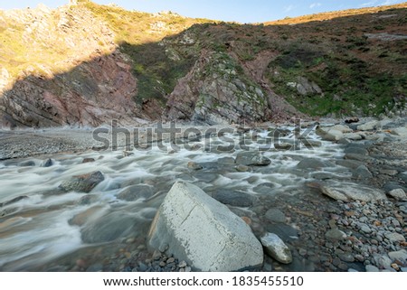 Long exposure of the river Heddon flowing onto the beach at Heddons Mouth in Exmoor