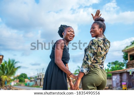 Two millennial African descent women laughing and having fun outdoors-focus on woman on left Royalty-Free Stock Photo #1835490556