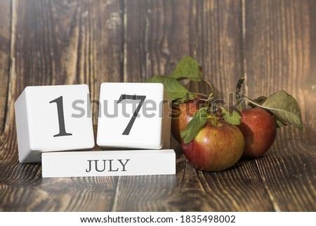 July 17. Day 17 of month. Calendar cube on wooden background with red apples, concept of business and an important event. Summer season.