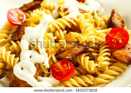 Close-up of pasta with chicken, tomatoes and cheese.