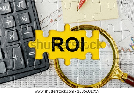 Business concept. Puzzle with a calculator, magnifying glasses and financial documents in the center inscription -ROI