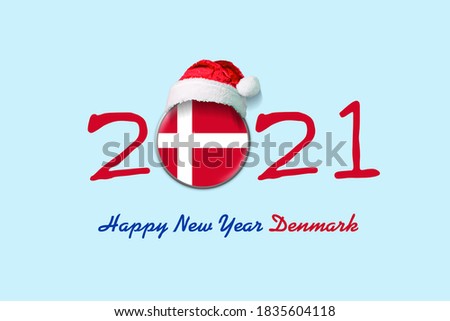 2021. Happy New Year Denmark. Flag of Denmark in a round badge, and in a Santa hat. Isolated on a light blue background. Design element. Festive background.
