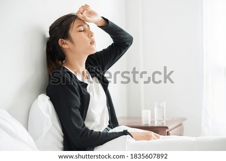 An uncomfortable woman sits on the bed and has medicine on the table. Royalty-Free Stock Photo #1835607892