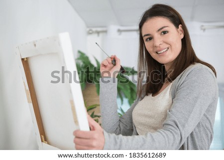 smiling woman using a screw on a wall