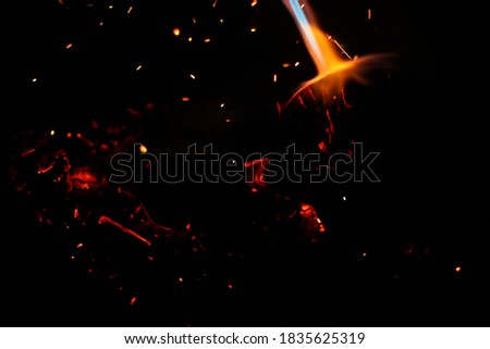 bokeh of blue fire of a gas burner, burning coals and sparks on a black background in the dark.