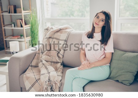 Photo portrait of young woman sitting on sofa with crossed legs indoors. Royalty-Free Stock Photo #1835630980