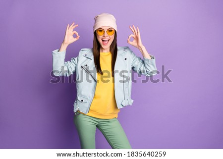 Portrait of crazy energetic girl enjoy excellent promo ads recommend, choose decide show okay sign wear yellow green pants isolated over purple color background