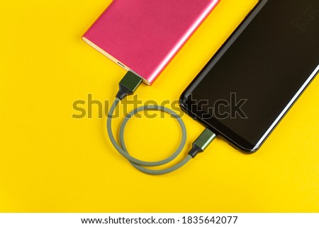 Smartphone Charging with Pink Power Bank on Yellow Background Top View