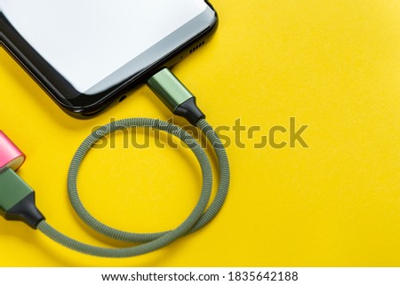 Charging a mobile phone on a yellow background.