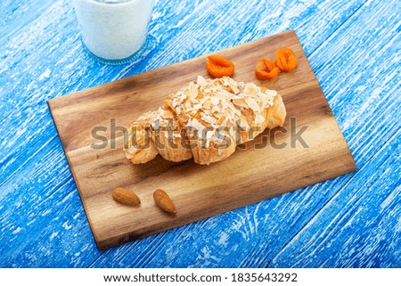 Fresh croissant with almonds on a wooden plank. French pastry