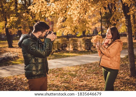 Photo of professional photographer guy take photo pretty girl hold maple orange, leaves in autumn september forest