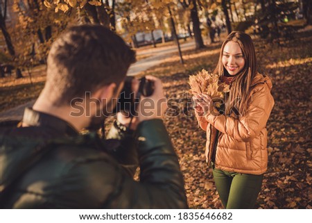 Photo of young guy taking, photo digital camera his beautiful girl hold maple leaves in fall september town park
