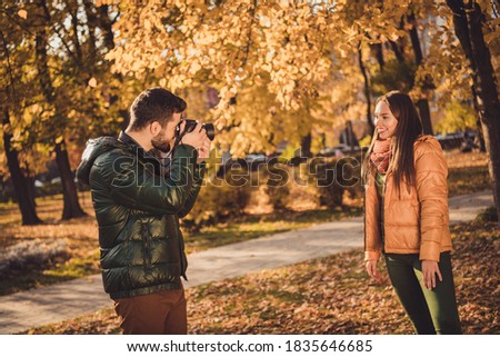 Photo of professional photographer guy, take photo of beautiful girl posing in fall october town park