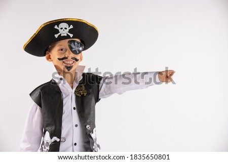 A smiling boy from kindergarten with a painted face saw something funny in the distance and shows everyone. He is dressed up for Halloween. Portrait on white background with empty side space