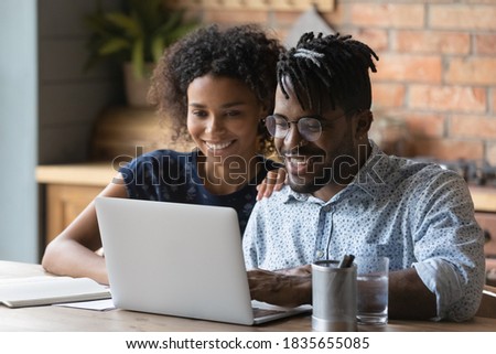 Happy young African American family look at laptop screen shopping on internet from home together. Smiling biracial couple manage budget pay bills taxes online on computer. Easy banking concept. Royalty-Free Stock Photo #1835655085