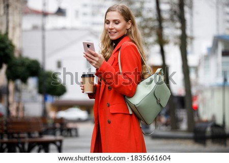 Attractive young woman walking outdoors, using mobile phone, texting, tapping and scrolling on mobile phone