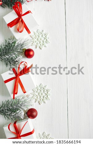 Christmas gift box, fir tree branches, red decorations on white wooden background