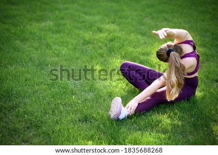Young sporty woman in sport dress does stretching exercises outdoor. Sunny. Outside, exhausted. USA