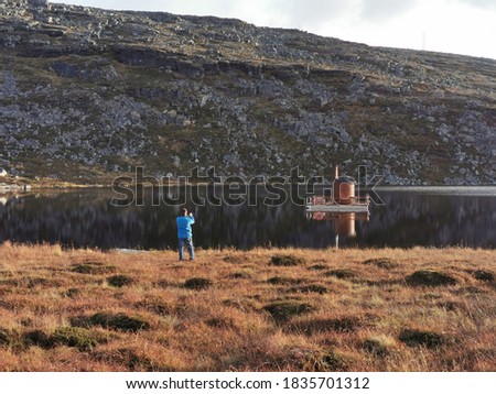 A man taking a picture of a sauna on the water