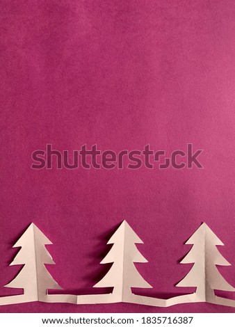 three pink Christmas trees cut from paper on a bright crimson background. minimalistic abstract new year concept.