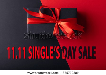 11.11 single day sale. Top view of black gift with red ribbon on half black color and half red color background.
