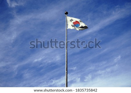 The Thai flag of Korea is fluttering in the wind on a clear sky.                               