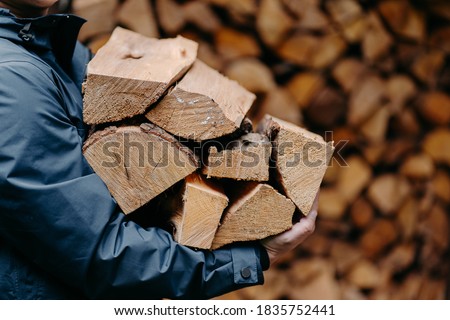 Unrecognizable man carries heap of wood for making fire dressed in jacket. Faceless male carries firewood into house Royalty-Free Stock Photo #1835752441