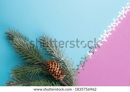 Minimalistic conceptual Christmas or New Year card with stars glitter and fir branch on trendy blue background with purple triangle.Top view with copy space.