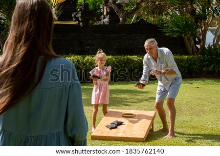 Family playing cornhole game outdoor on sunny summer day. Parents and children playing bean bag toss Royalty-Free Stock Photo #1835762140